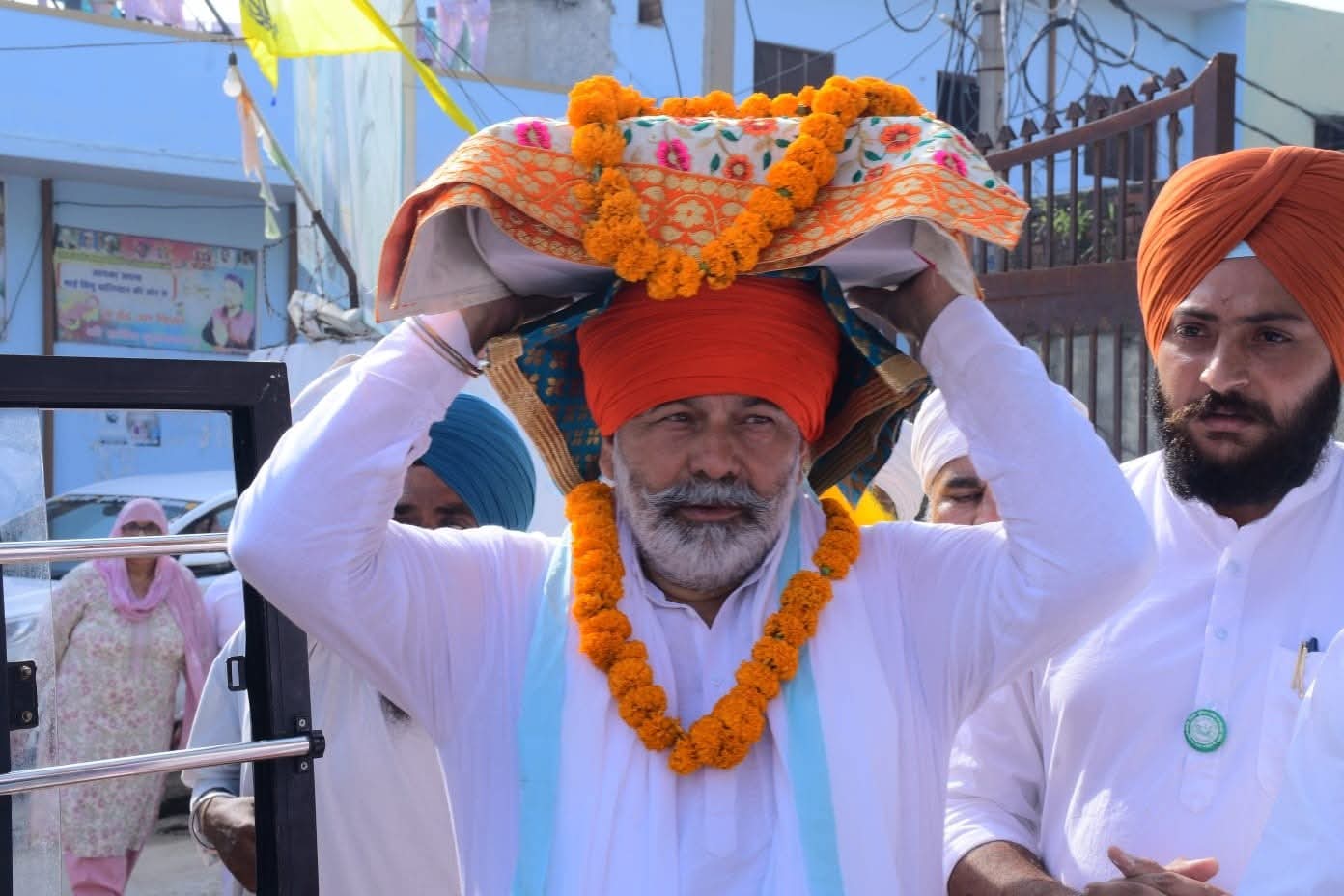 चौधरी राकेश टिकैत सिसौली में अखंड पाठ साहिब के दौरान श्री गुरु ग्रंथ साहिब जी को सिर पर धारण किए हुए
